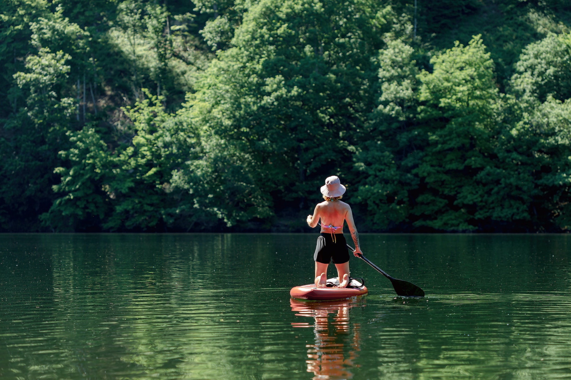 young woman floating down the river on a paddle board